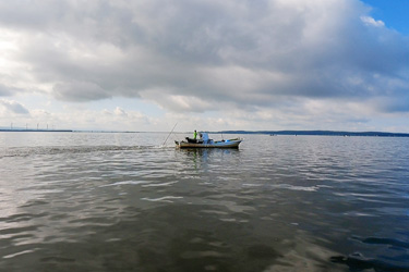 十三湖水面で漁船を操縦する漁師